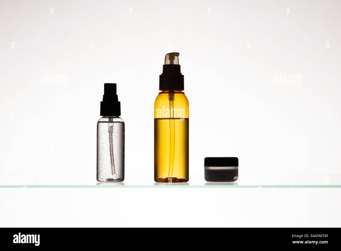 Verschiedene kosmetische Produkte auf einem Glasregal auf weißem Hintergrund. Mockup von Hautpflege- und Badeprodukten auf einem Glasregal. Spender und Röhrchen Stockfoto