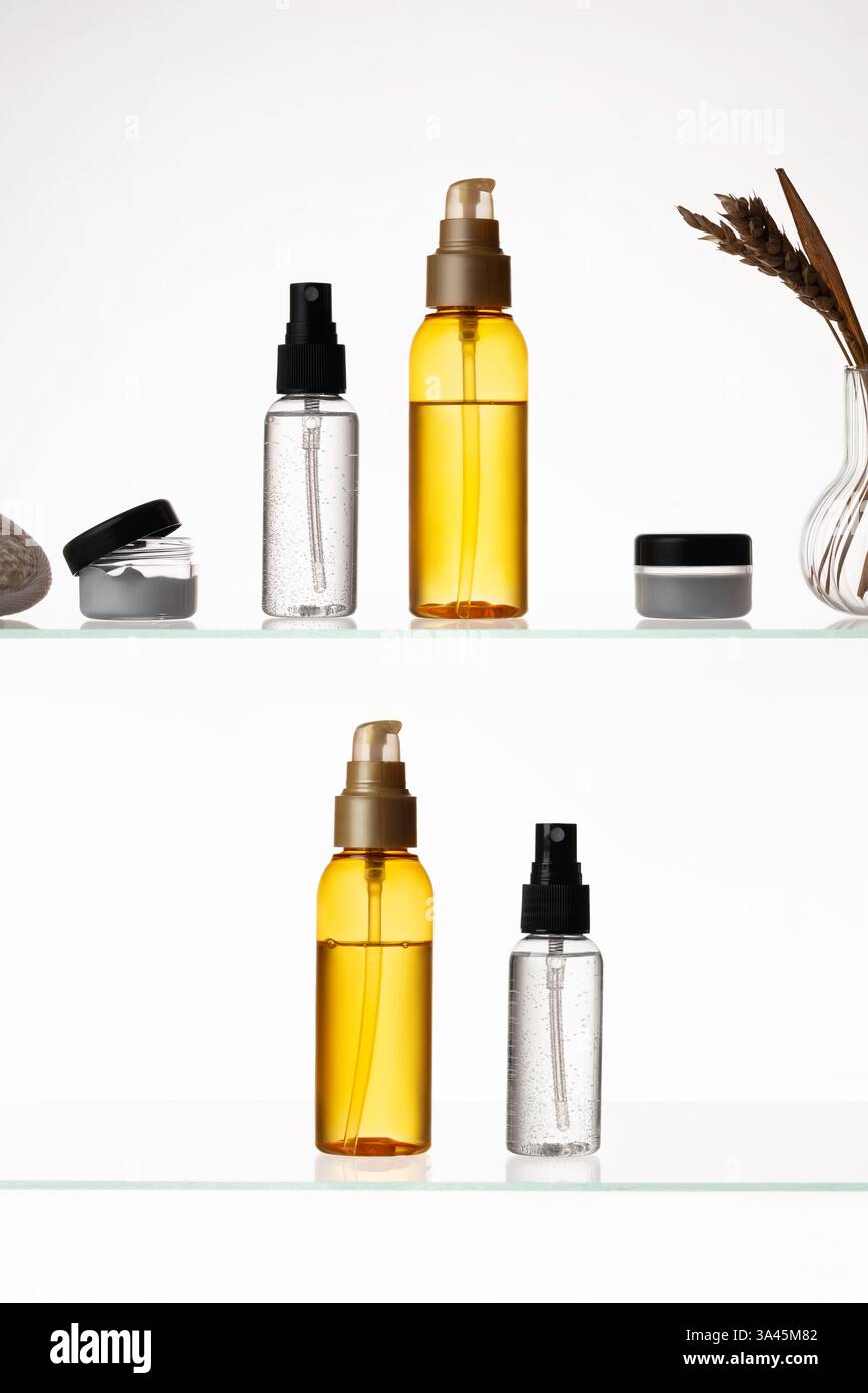 Viele Kosmetikprodukte auf einem Glasregal auf weißem Hintergrund. Mockup von Hautpflege- und Badeprodukten auf einem Glasregal. Spender und Röhrchen Stockfoto
