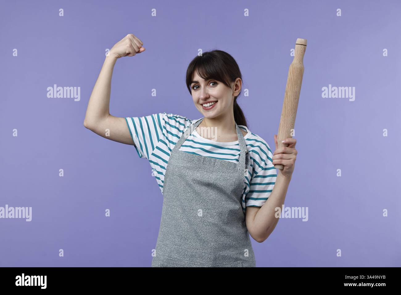 Eine Frau mit einem Pin, der Stärke auf violettem Hintergrund zeigt Stockfoto