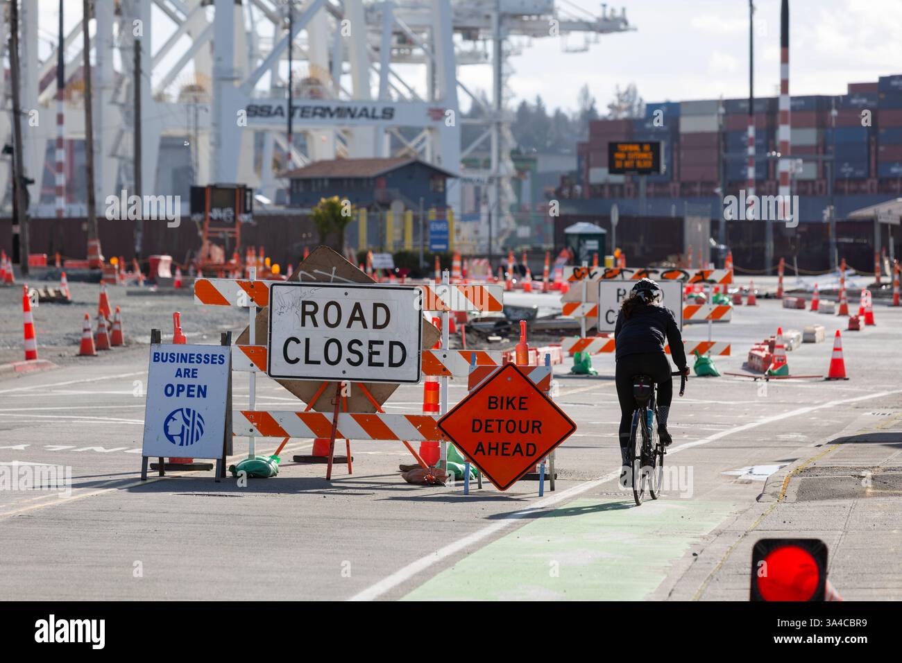 Ein Radfahrer macht am Sonntag, den 16. März 2025, einen Radumweg durch eine Bauzone entlang des Alaska Way S im Stadtteil SoDo von Seattle. Der Östliche Rand Stockfoto