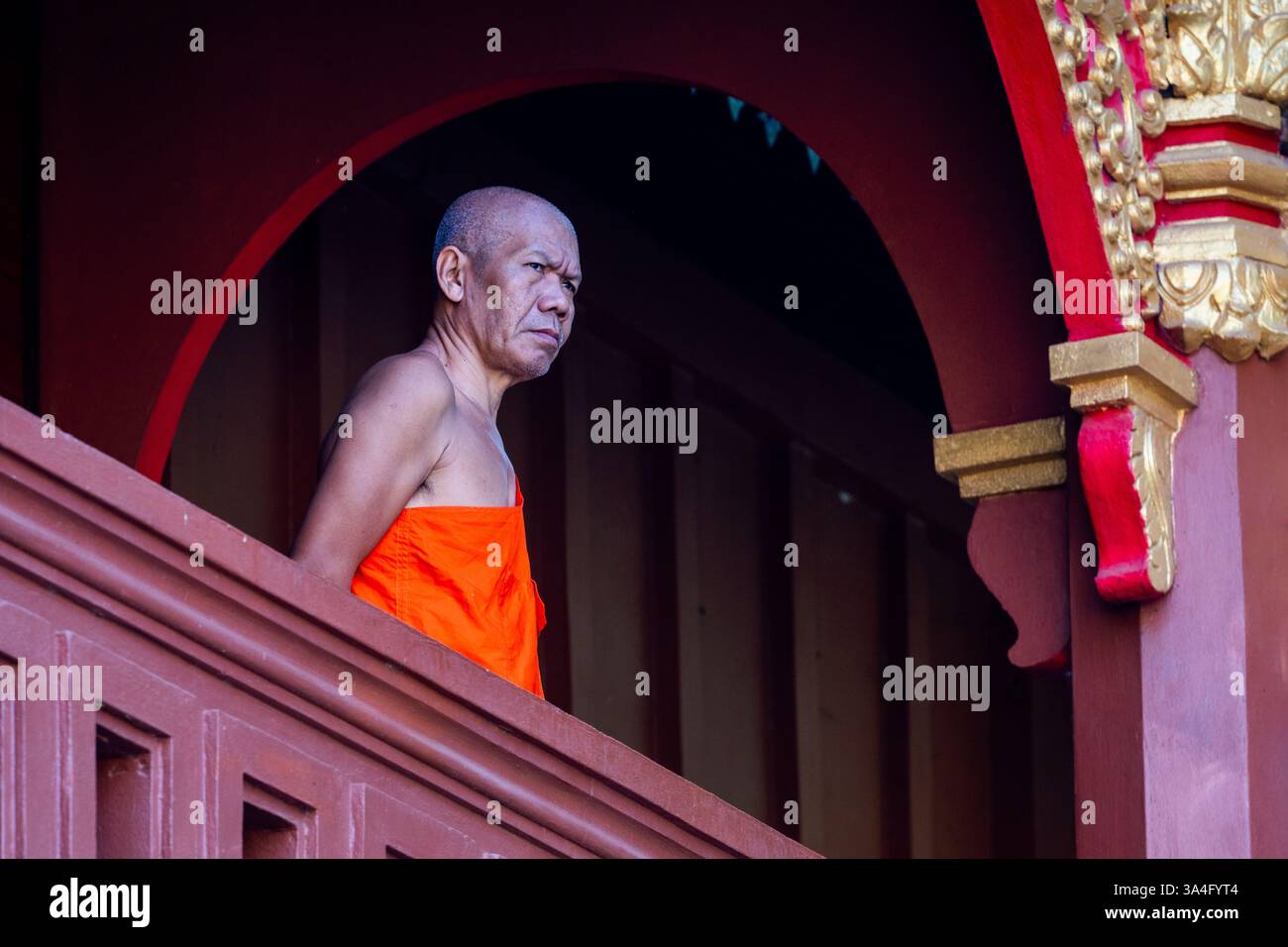 Ein buddhistischer Mönch steht in einem traditionellen laotischen Tempel und fängt die kulturelle Essenz und spirituelle Gelassenheit Laos ein Stockfoto
