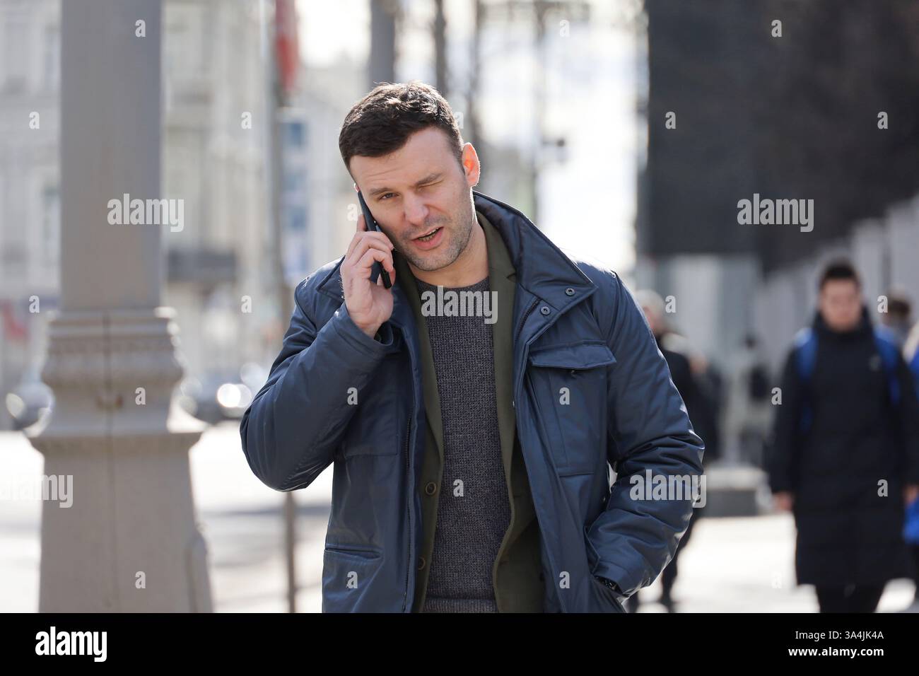 Junger Mann, der im Frühjahr auf der Straße in der Stadt telefoniert Stockfoto