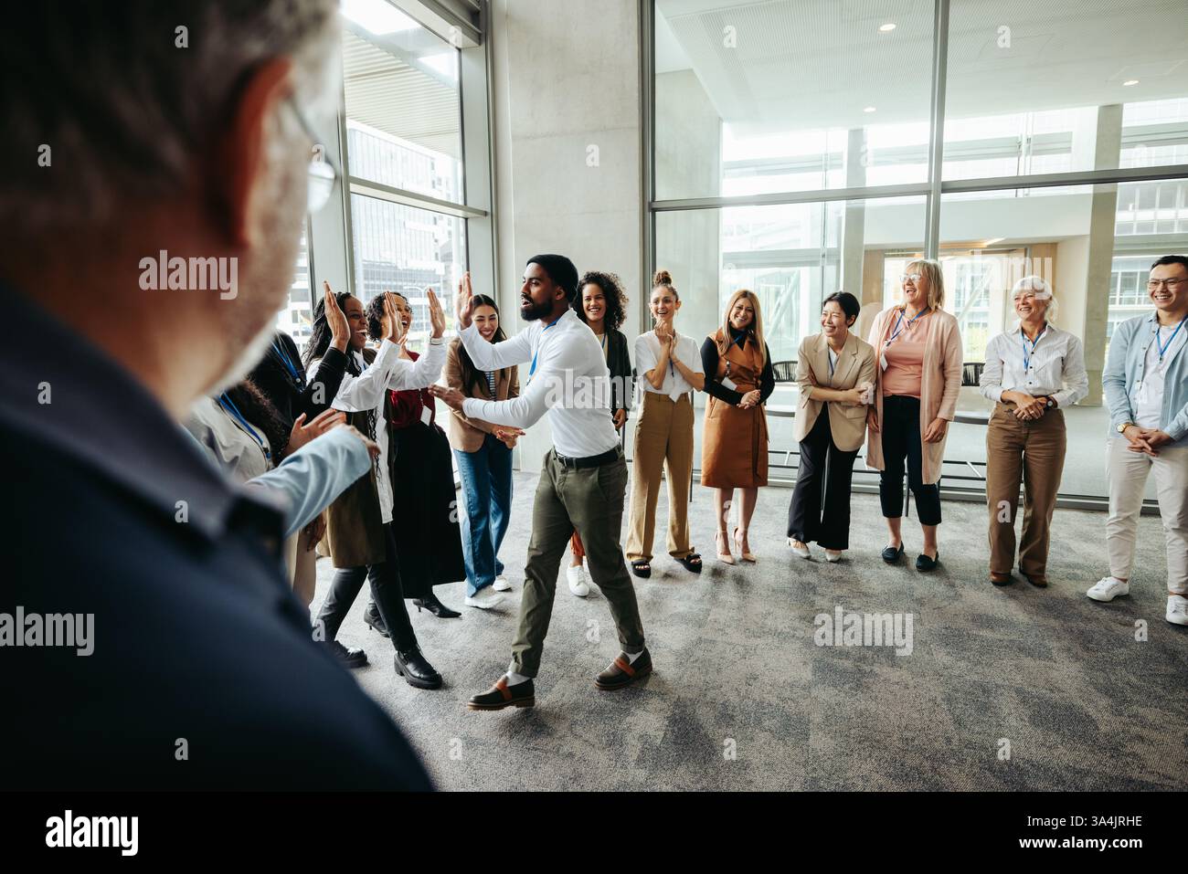 Chef feiert mit Mitarbeitern, gibt High Fives in einem modernen Büro. Das Team genießt einen Moment der Anerkennung und Leistung in einem Arbeitsumfeld Stockfoto