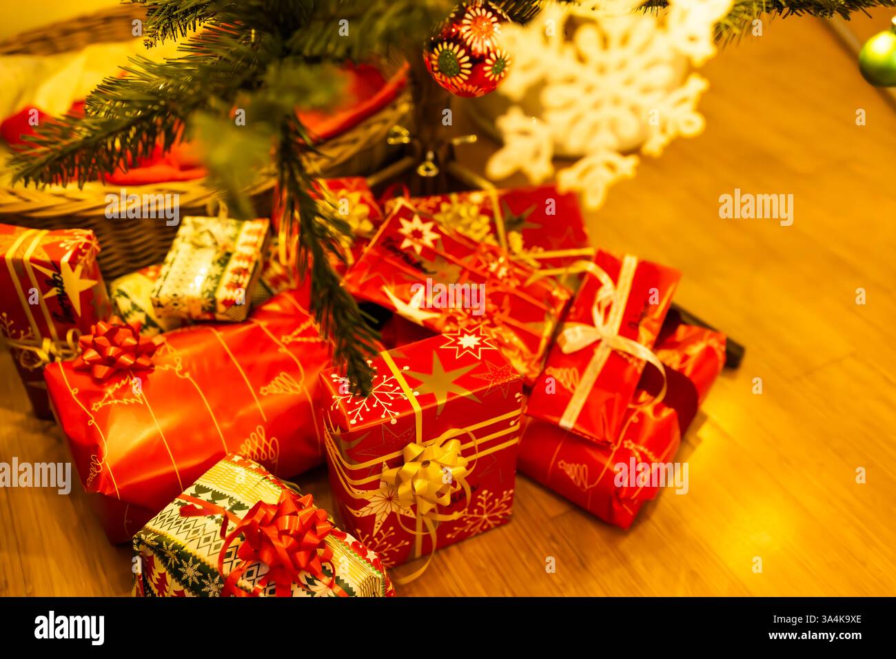 Haufen eingewickelter Weihnachtsgeschenke unter dem verzierten Baum Stockfoto
