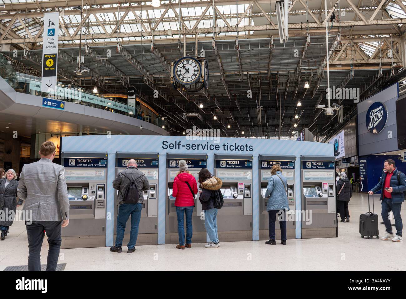 Personen oder Passagiere, die Bahnfahrkarten an Selbstbedienungsautomaten im Bahnhof Waterloo, London, England, Großbritannien kaufen Stockfoto