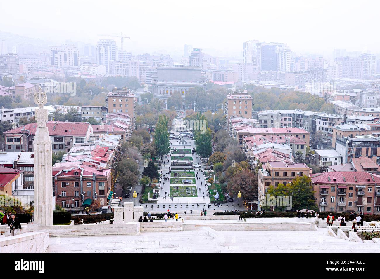 Ein nebeliger Blick vom Kaskadenkomplex in Jerewan mit Blick auf einen lebhaften Park und die Architektur der Stadt. Das symmetrische Design und sanfte Herbsttöne Stockfoto