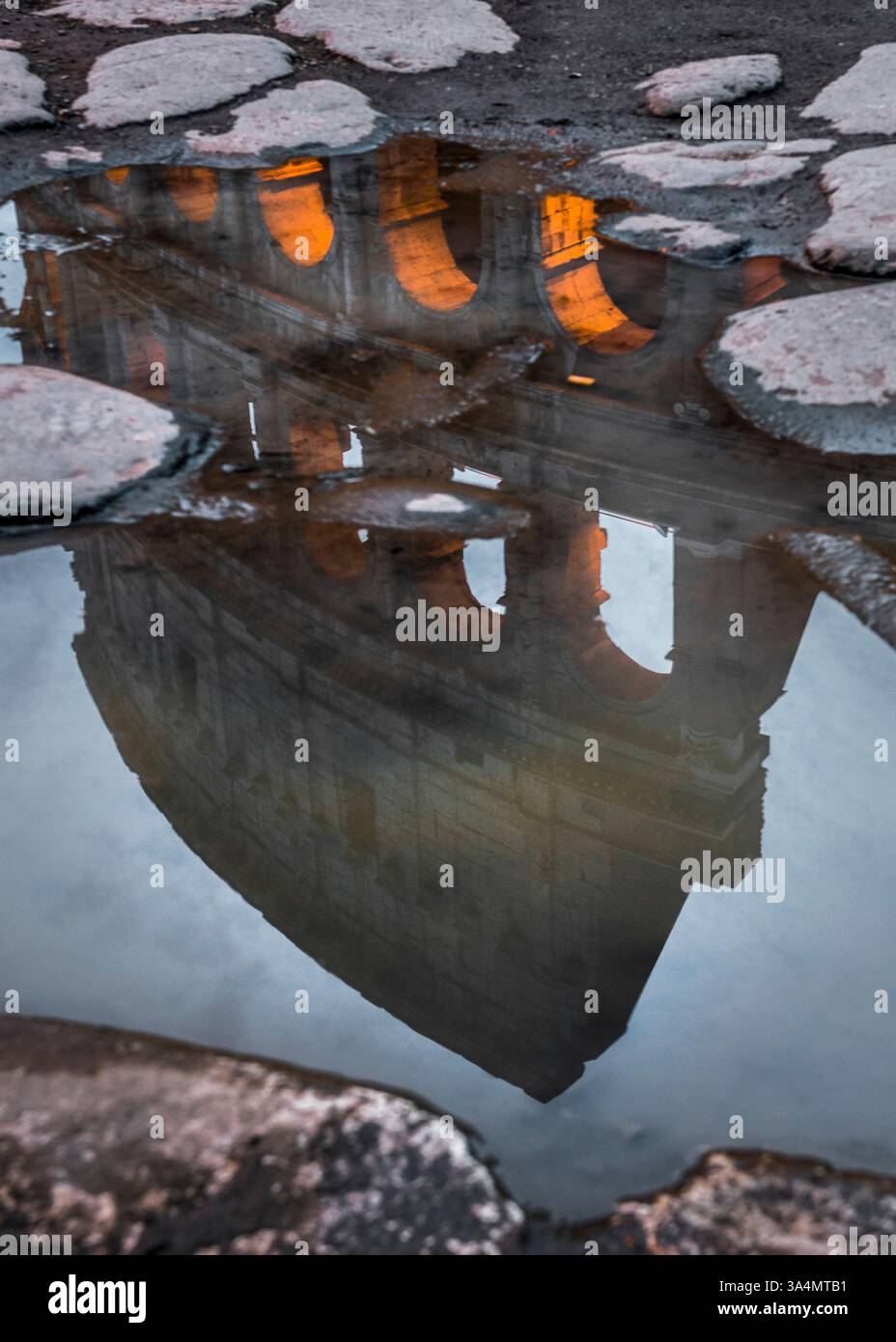 Das Kolosseum von Rom spiegelt sich in einer Pfütze wider. Stockfoto