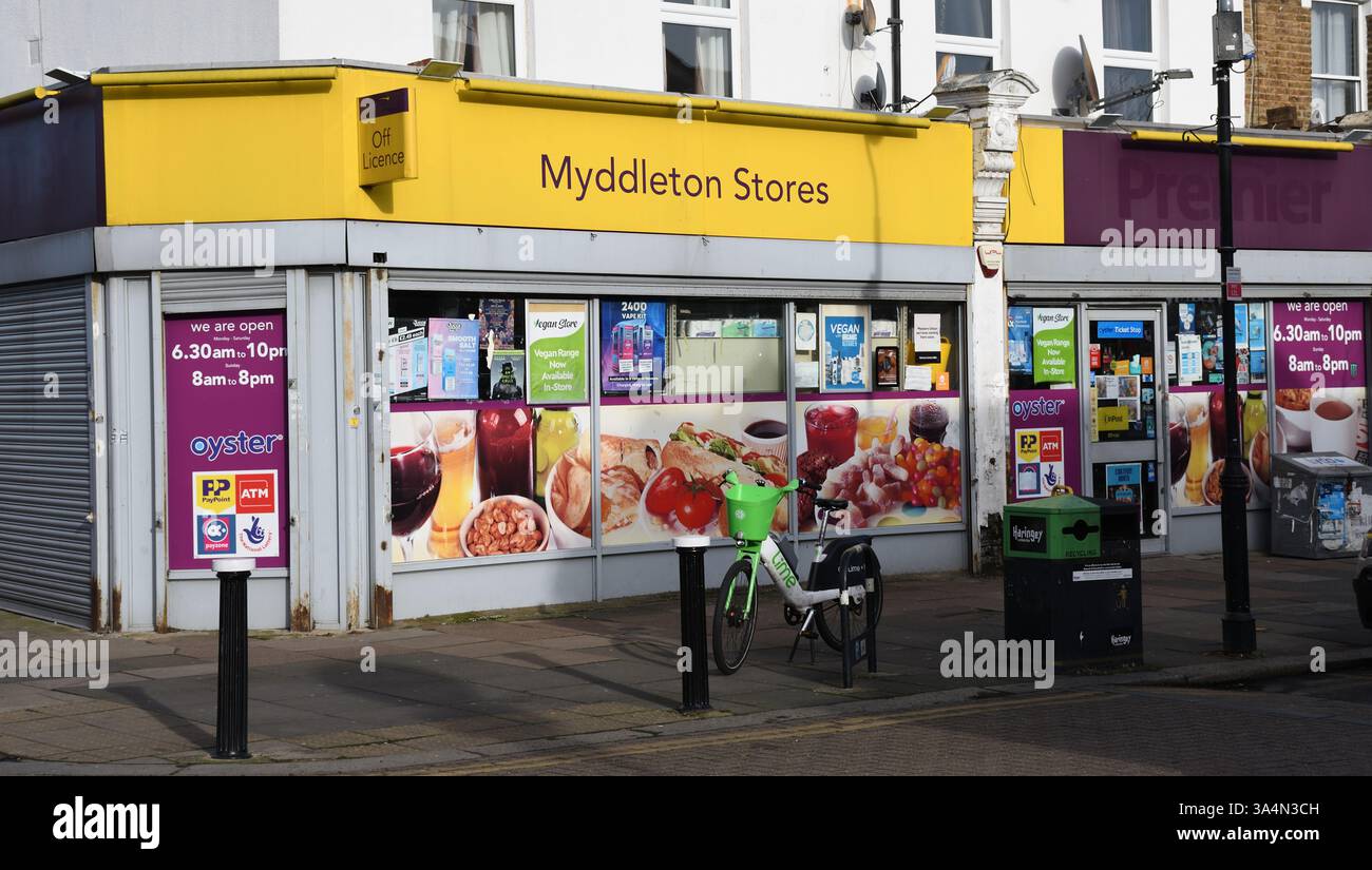 Lokaler Supermarkt, Bounds Green, North London, London, Vereinigtes Königreich - hellfarbige gelbe Markise, Widnows mit Werbung bedeckt; Fahrrad für Verleih Stockfoto