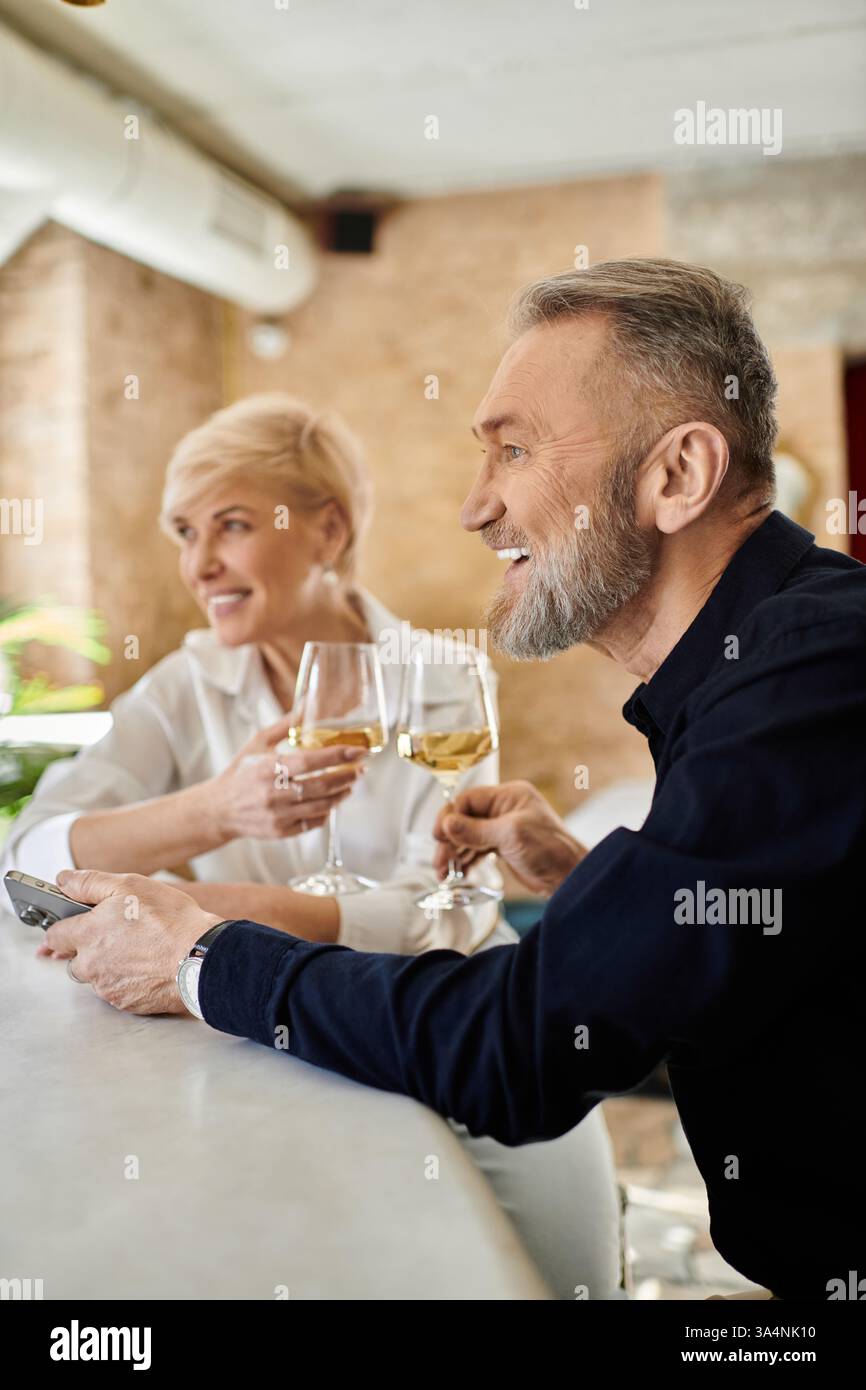 Ein Paar mittleren Alters teilt sich Getränke und lächelt in einer gemütlichen Bar. Stockfoto