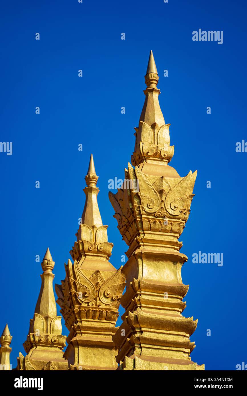 Goldene Türme vor einem leuchtend blauen Himmel in Laos, die die exquisite Architektur und spirituelle Bedeutung der Tempel der Region zeigen Stockfoto