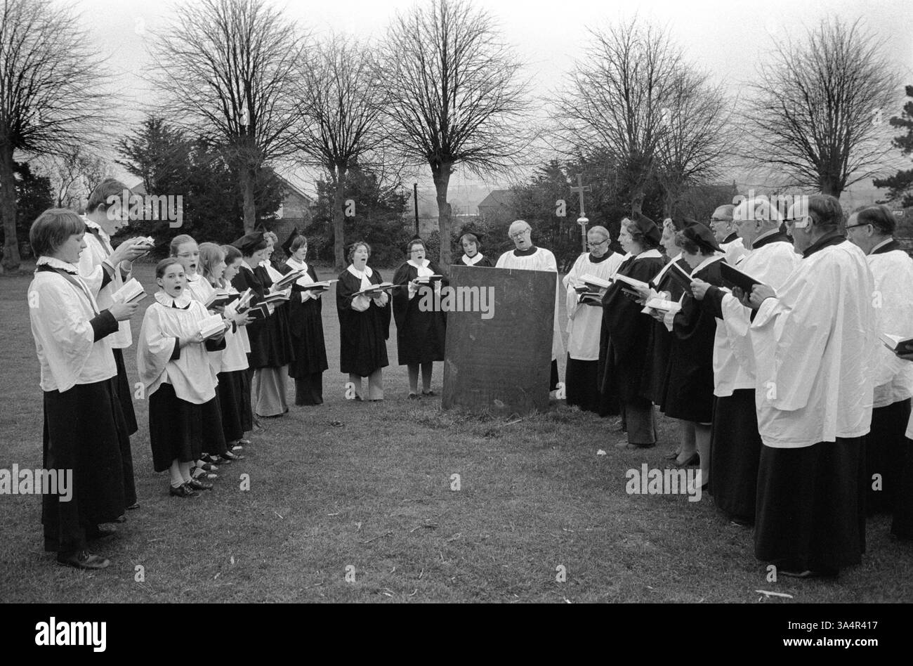 William Hubbard Gedenkgottesdienst am Ostersamstag. Der Chor der St. Dionysius Church versammelt sich an den Ruinen der alten Kirche St. Mary in Arden in Market Harborough, um an den ehemaligen Kirchenleiter William Hubbard zu erinnern und seine letzten Wünsche durch Singen zu erfüllen. Jesus Christus ist heute an seiner Grabstätte auferstanden. Er starb 1786 und seither findet der Sonderdienst jährlich statt. Market Harborough, Leicester, England, 1976 1970er Jahre Großbritannien HOMER SYKES Stockfoto