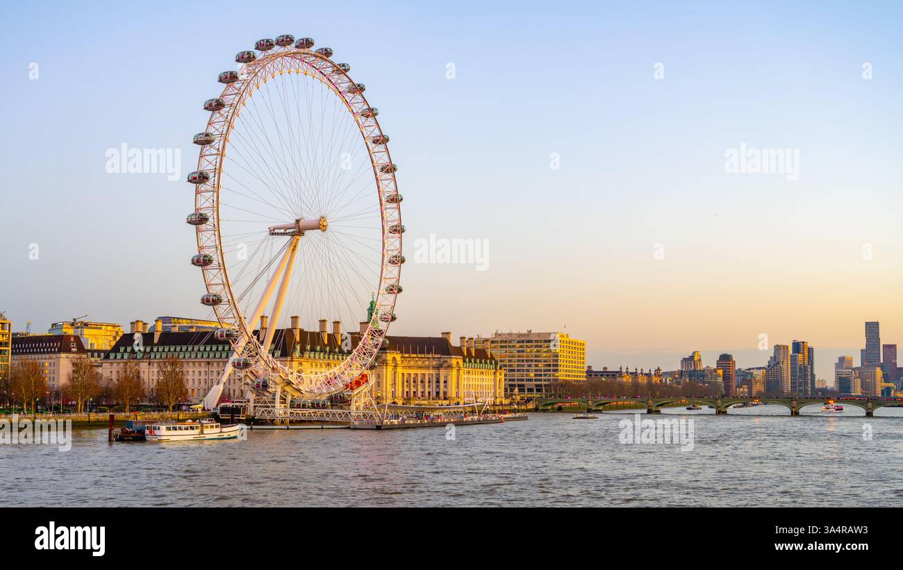 Das berühmte London Eye ragt über die Themse und bietet einen Panoramablick auf die Stadt. Besucher genießen gemütliche Bootsfahrten, während der Himmel in abendliche Farben übergeht. Stockfoto