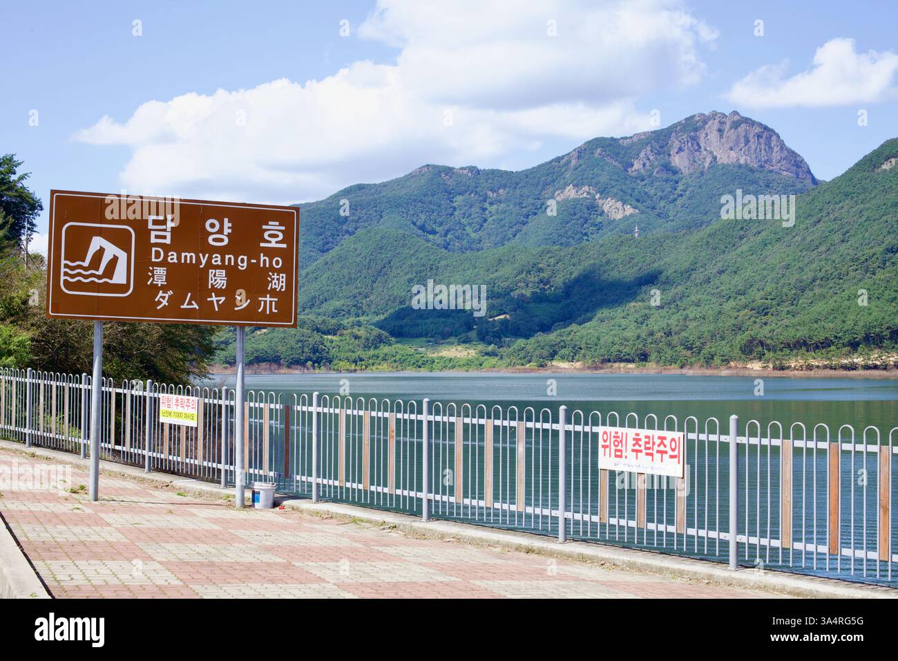 Damyang County, Südkorea - 23. September 2020: Ein braunes Straßenschild markiert den Eingang zum Damyang See, mit dem ruhigen Wasser des Stausees reflektiert Stockfoto