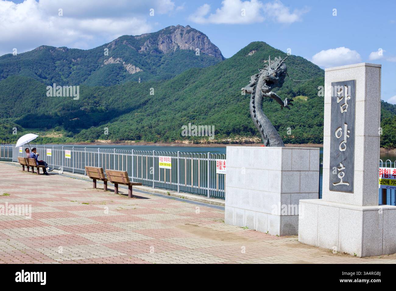 Damyang County, Südkorea - 23. September 2020: Am Rand des Damyang Sees steht eine bronzene Drachenstatue mit dem Jeonggak-Berg im Hintergrund. Stockfoto