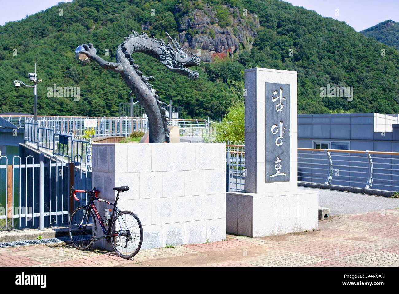 Damyang County, Südkorea - 23. September 2020: Ein Rennrad lehnt sich an die Basis einer Drachenstatue am Damyang See, mit der malerischen Kulisse von t Stockfoto