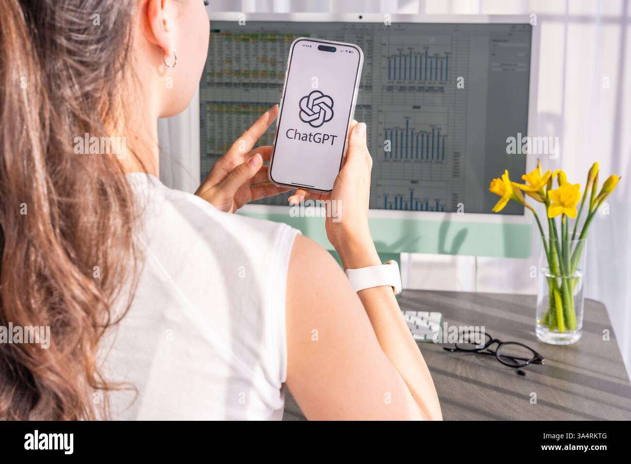 Prag, Tschechische republik - 24. Februar 2025: Junge Frau, die eine ChatGPT-App auf ihrem Smartphone verwendet, während sie zu Hause arbeitet. KI-betriebene Assistenten verbessern die Leistung Stockfoto