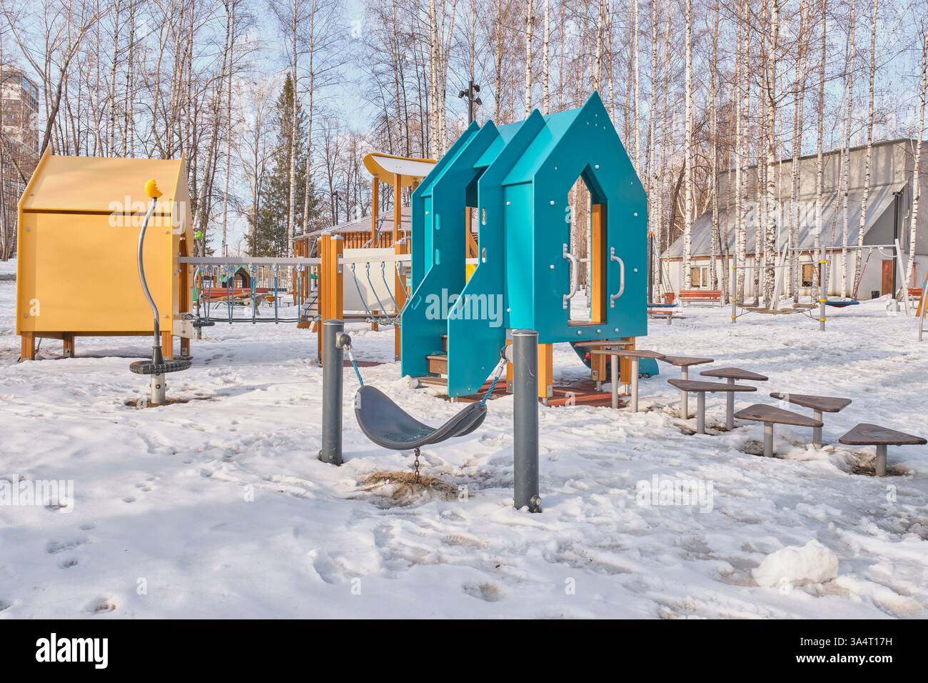 Jekaterinburg, Russland - 17. März 2025: Lebendiger Kinderspielplatz mit blauen und gelben Spielstrukturen, Kletterausrüstung und Balance-Plattformen c Stockfoto