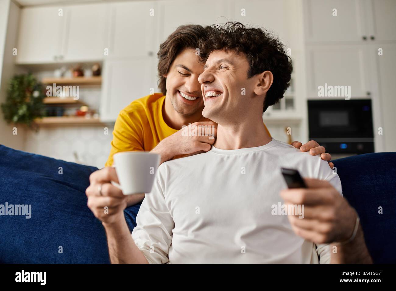 Zwei schwule Männer teilen fröhliche Momente in ihrem stilvollen Apartment, in dem sie Liebe und Verbundenheit genießen. Stockfoto