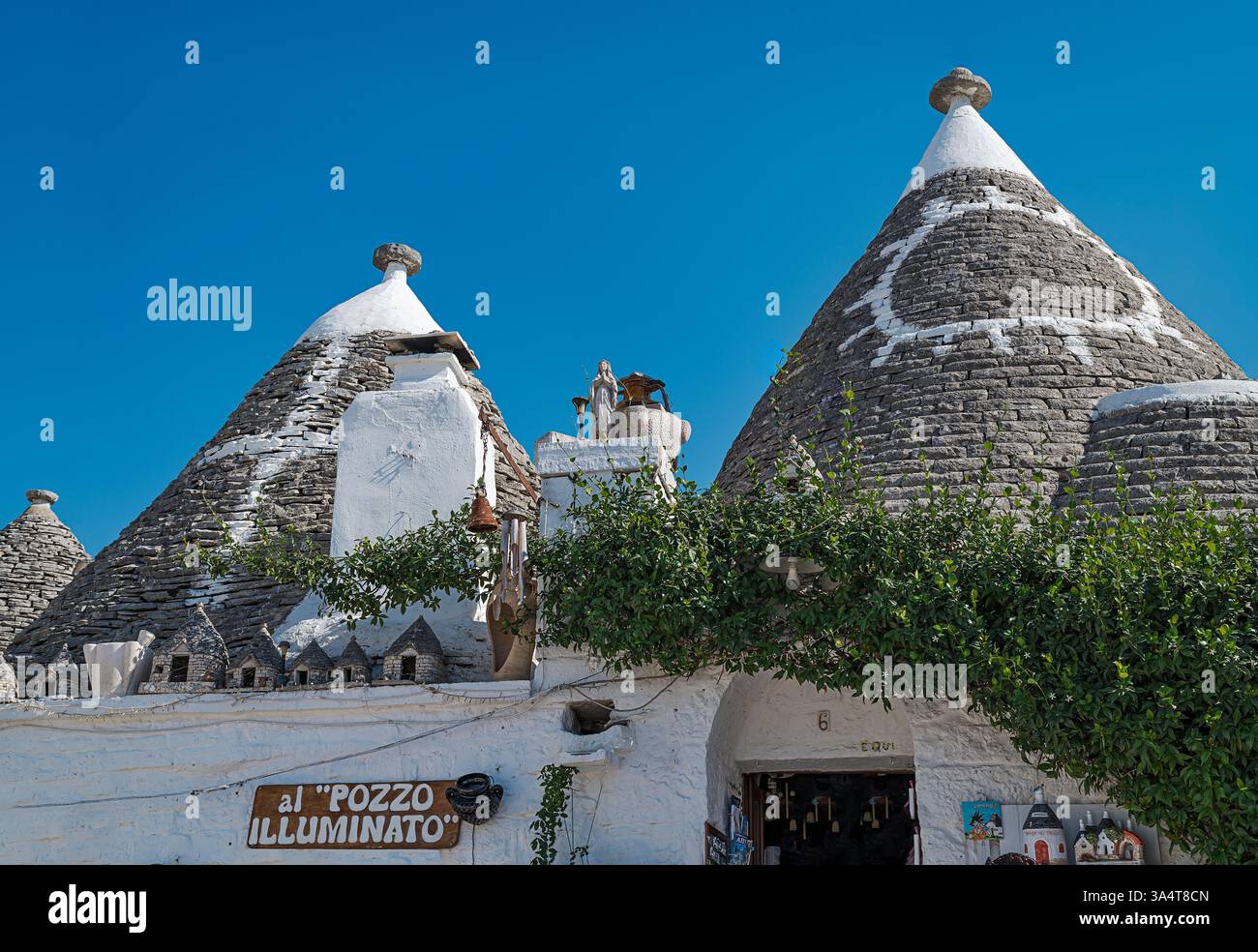 Malerisch von traditionellen Trulli-Häusern in Alberobello, Italien, mit konischen Steindächern. Terrasse mit Panoramablick. Der hellblaue Himmel fügt hinzu Stockfoto