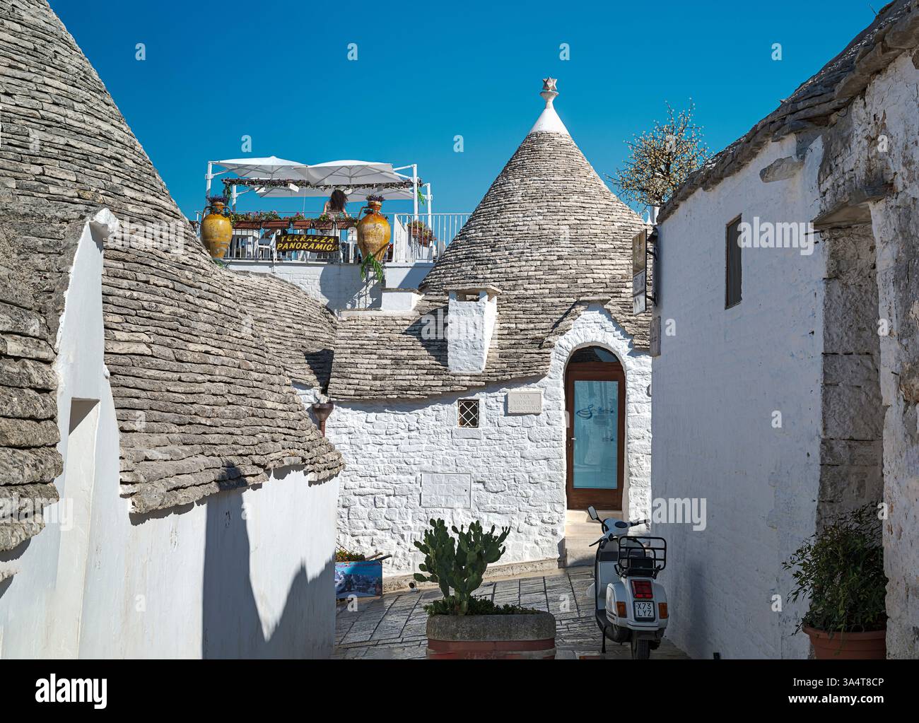Malerisch von traditionellen Trulli-Häusern in Alberobello, Italien, mit konischen Steindächern. Terrasse mit Panoramablick. Der hellblaue Himmel fügt hinzu Stockfoto