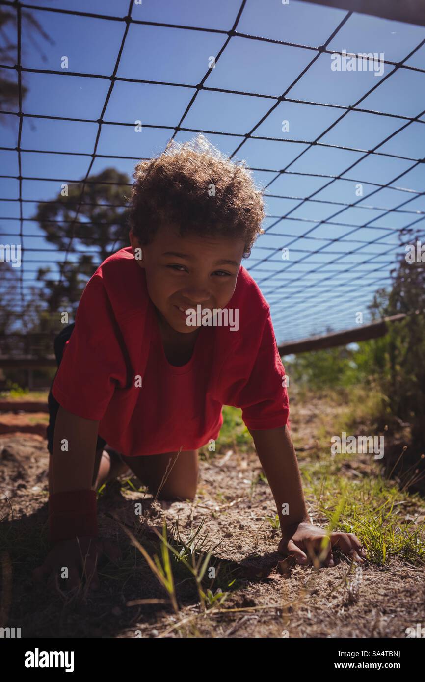 Kinder krabbeln unter dem Netz im Freien, lächeln und genießen Bootcamp-Aktivitäten Stockfoto