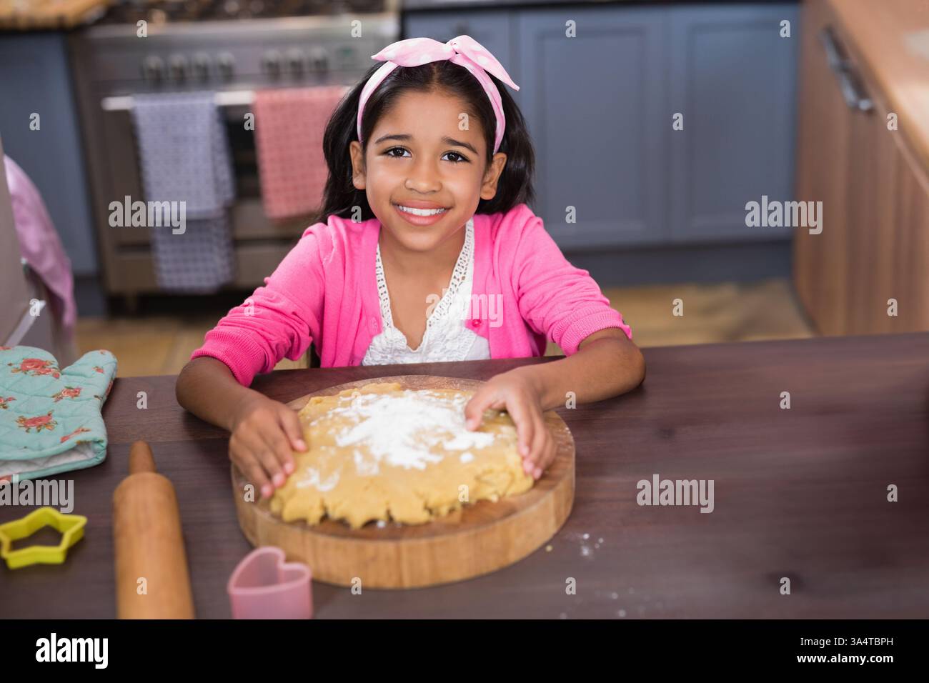 Lächelndes Mädchen, das zu Hause Teig backt und Spaß an der Küche hat Stockfoto