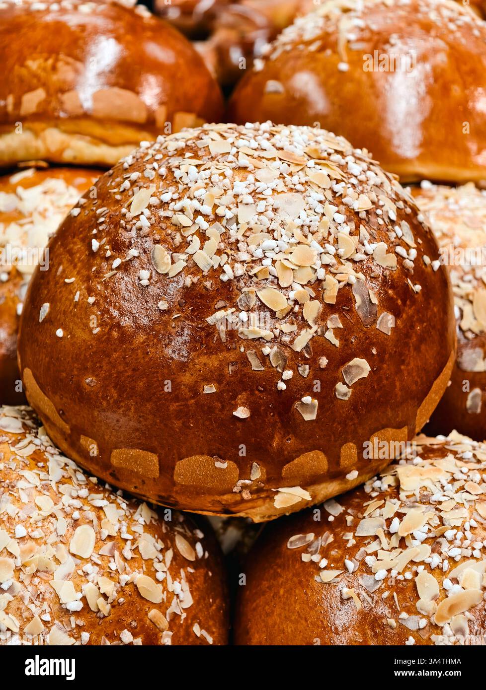 Frisch gebackene goldbraune Brötchen mit Mandelscheiben und Zuckerkristallen, perfekt für Backwarenaktionen, Food Blogs und kulinarische Projekte mit köstlichem Gebäck Stockfoto