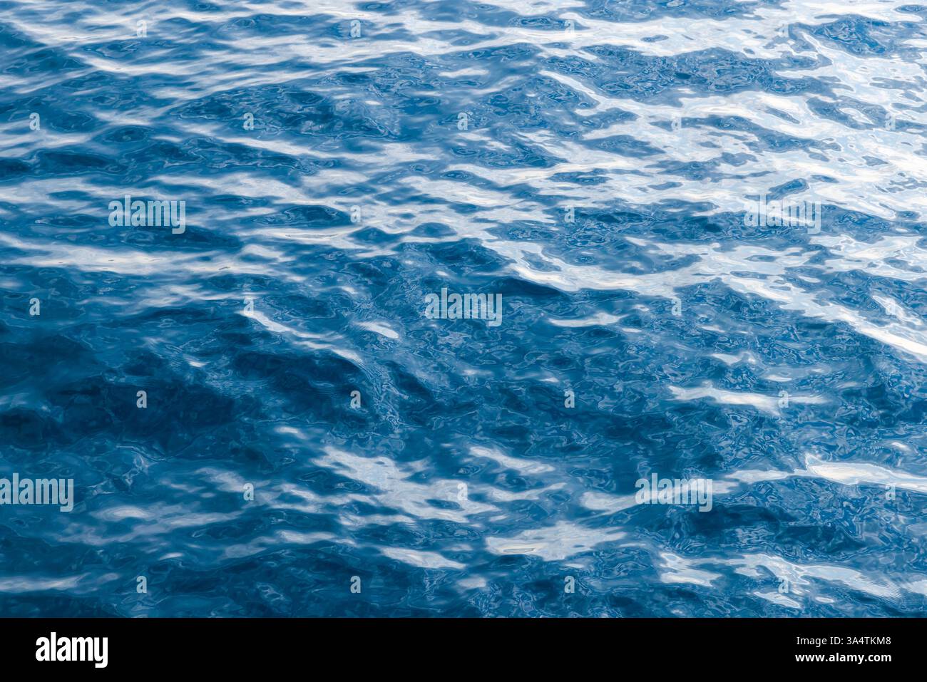 Die ruhige Meeresszene zeigt das Zusammenspiel von Sonnenlicht auf plätscherndem Wasser und schafft ruhige Muster Stockfoto