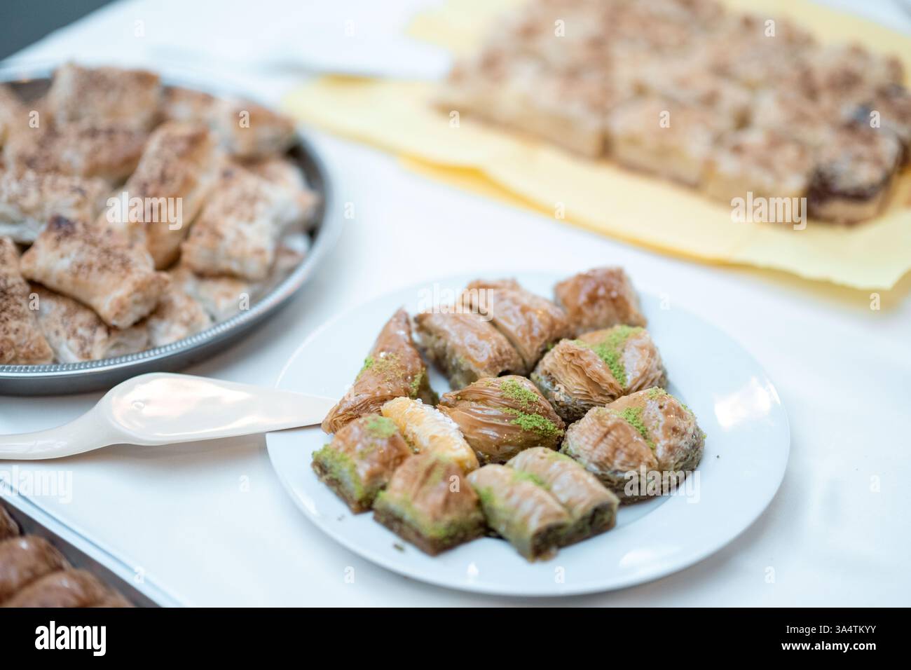 Düsseldorf, Deutschland. März 2025. Traditionelle Backwaren werden auf Teller gelegt, bevor Christen und Muslime in der evangelischen Mirjam-Kirche ihr Fasten brechen. In diesem Jahr überschneiden sich die Fastenzeiten von Muslimen und Christen. Die Kampagne soll Ähnlichkeiten hervorheben und das Verständnis fördern. Quelle: Fabian Strauch/dpa/Alamy Live News Stockfoto