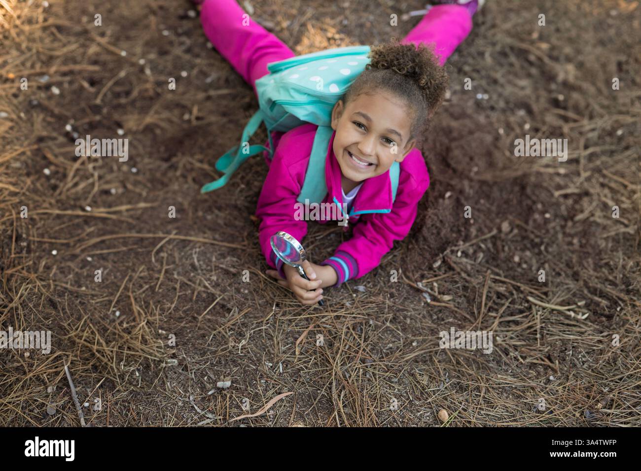 Waldboden erkunden, Kind in rosa Outfit mit Lupe, fröhlich lächelnd, Kopierraum Stockfoto