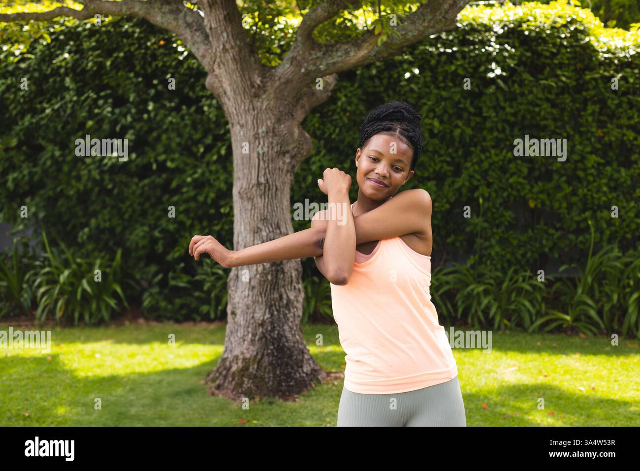 Frau, die Arme im Garten streckt, Outdoor-Übungen unter Bäumen genießt, Kopierraum Stockfoto