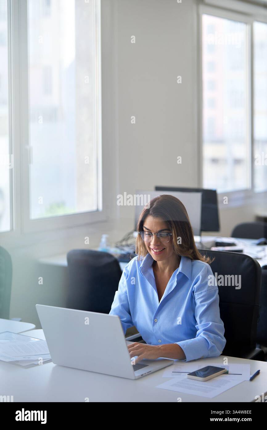 Glückliche professionelle Geschäftsfrau mittleren Alters, die im Büro einen Laptop benutzt. Stockfoto