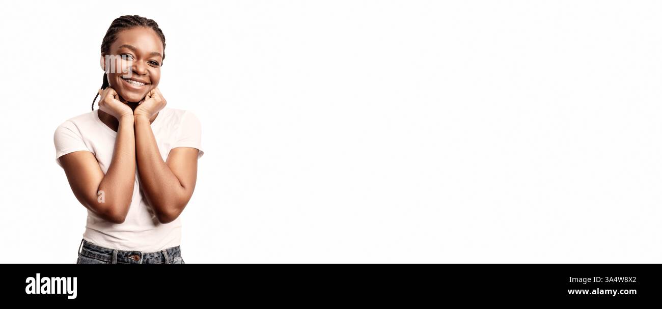 Junge Frau lächelt mit Händen auf Gesicht in hellem Studio-Setting Stockfoto