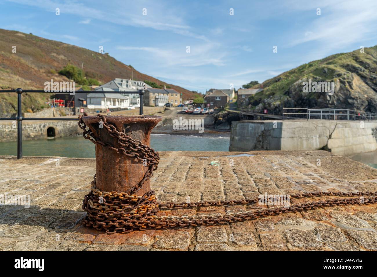 Der malerische Hafen von Mullion Cove auf der Lizard Peninsula mit seiner berühmten rostigen alten Capstan und Kette Stockfoto