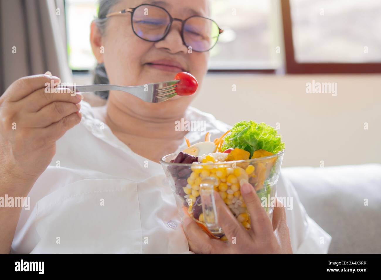 Schuss von glücklicher reifer asiatischer Seniorin, die zu Hause gesundes Essen isst. Das Konzept der gesunden Ernährung im Ruhestand. Kopierbereich, selektiver Fokus. Stockfoto
