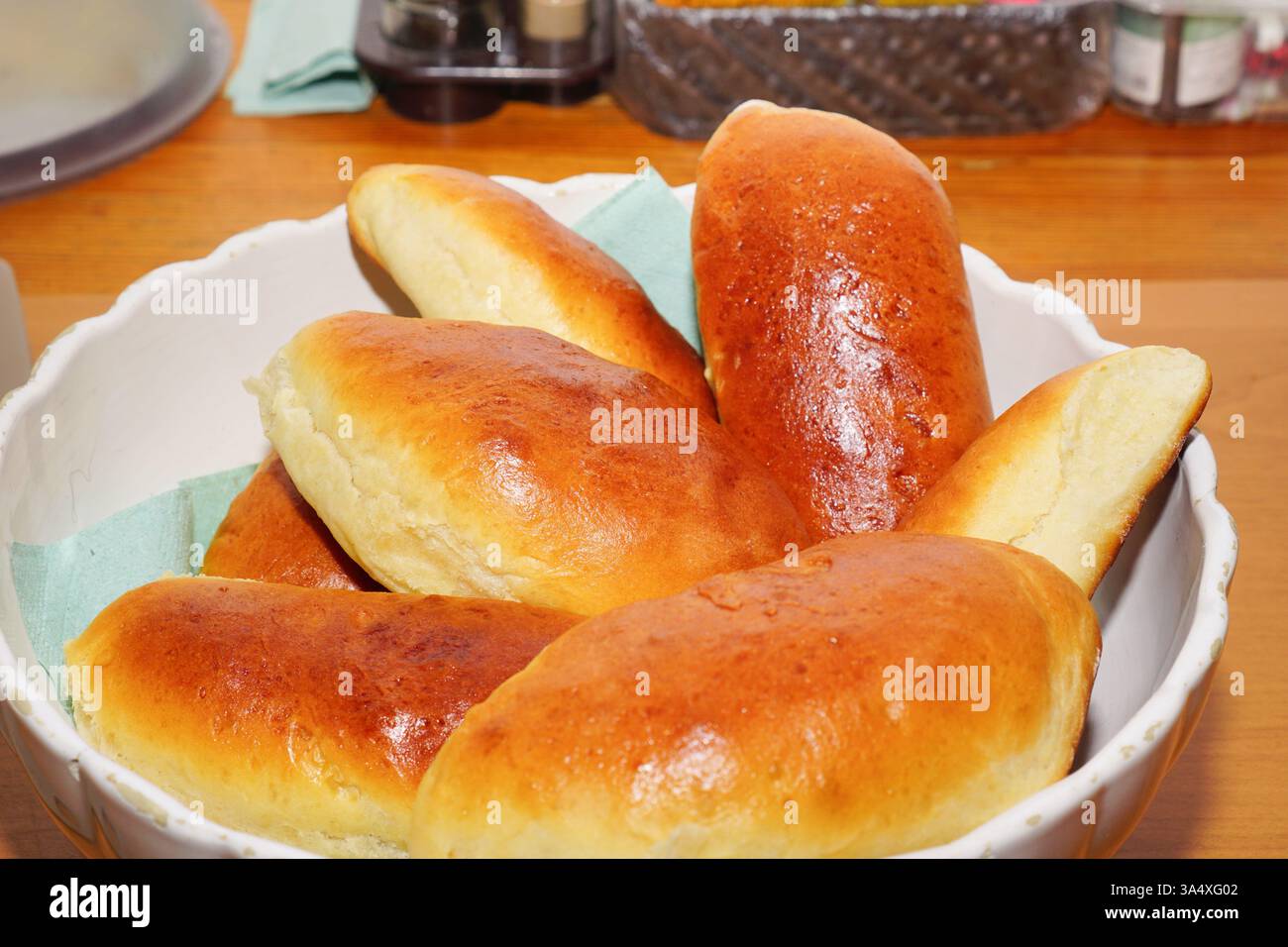 Frisch gebackene hausgemachte Kuchen mit goldbrauner Kruste in einer weißen Schüssel auf einem rustikalen Holztisch. Die warme, blättrige Textur und das reichhaltige Aroma vermitteln ein Gefühl von Wohnkomfort und traditionellem Backen. Konzept des hausgemachten Backens, traditionelle Küche, Komfortgerichte. Stockfoto