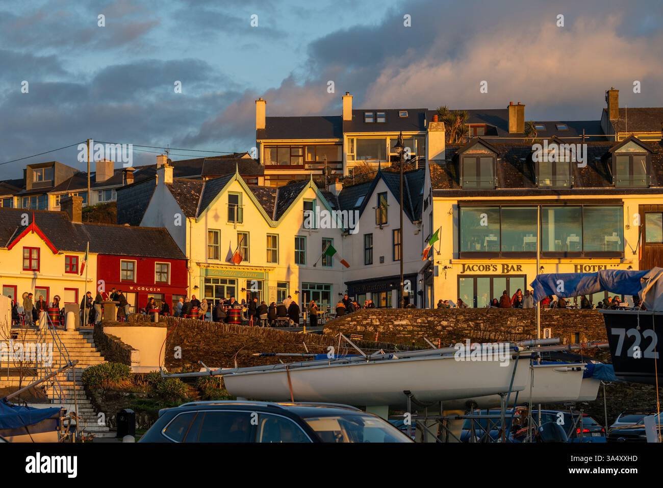 Menschen, die trinken, wenn die Sonne untergeht auf einem voll bepackten Platz in Baltimore, West Cork, Irland. Stockfoto