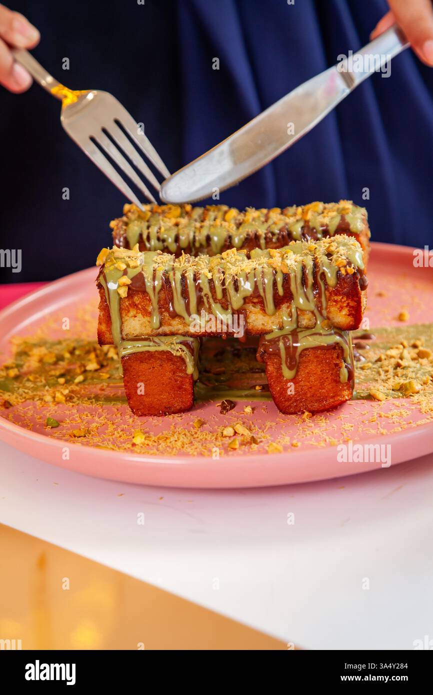 französischer Zimt-Toast mit Pistazienbelag, serviert mit Milchshake in einem schicken Café-Restaurant. Stockfoto