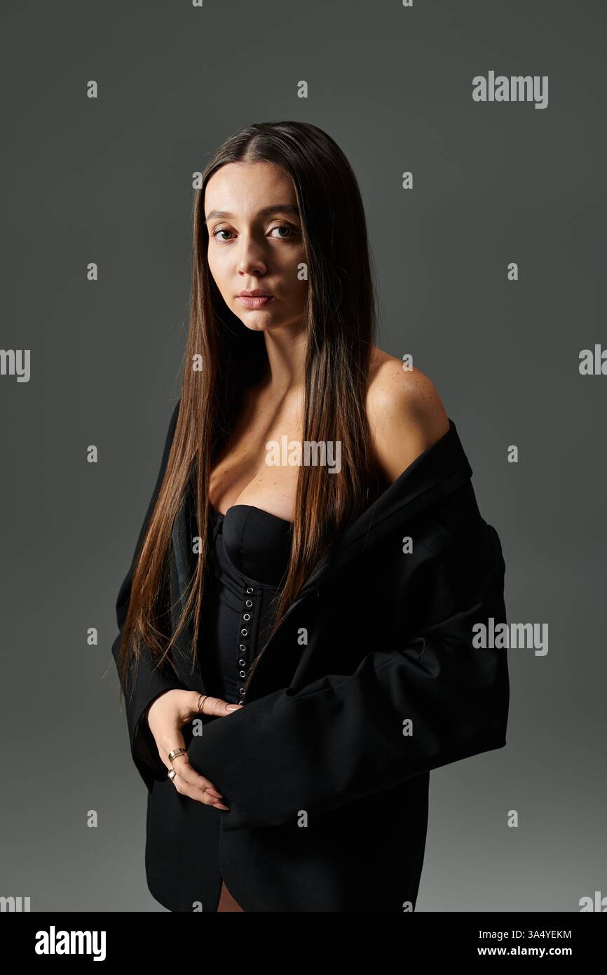 Eine schöne junge Frau zeigt ihre Gymnastik in stilvoller Kleidung vor einem einfachen Hintergrund. Stockfoto