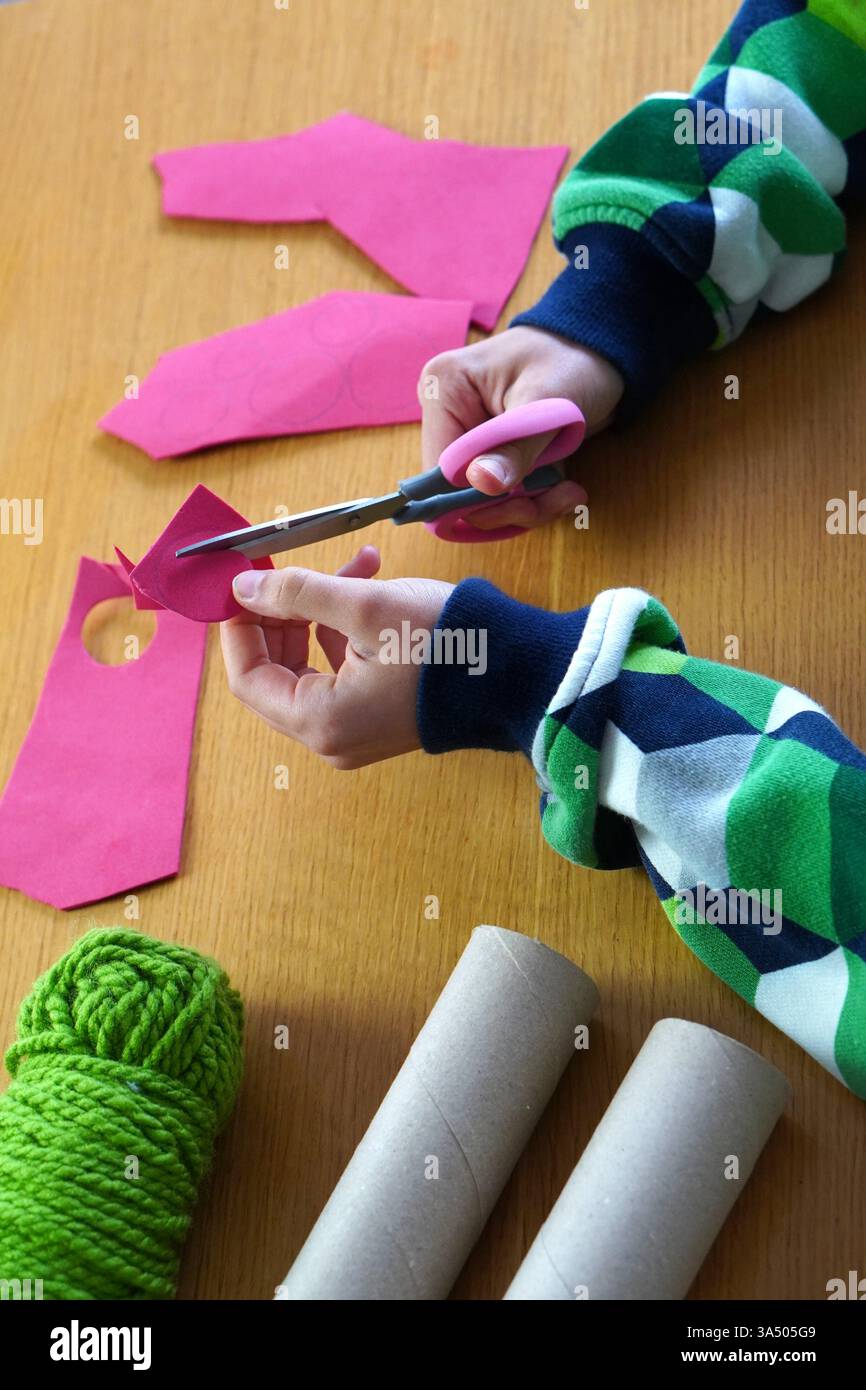 Kinderhände basteln mit recycelten Materialien, indem sie Teile aus eva-Gummi herausschneiden. Stockfoto