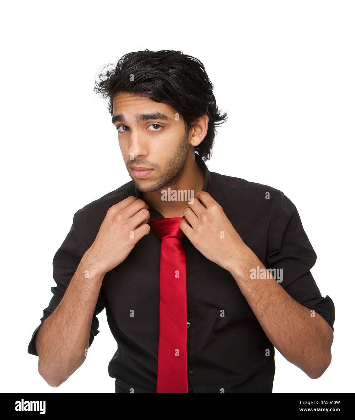 Nahporträt eines stilvollen Indianers, der seinen Hemdkragen vor weißem Hintergrund anpasst. Der klare, moderne Look passt zu Unternehmens-, Mode- und Privatmarkenkampagnen. Ein selbstbewusstes, ansprechendes Porträt mit starker geschäftlicher Attraktivität. Stockfoto