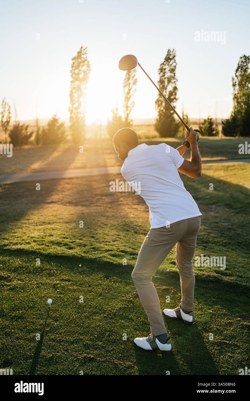 Hispanischer Golfspieler, der auf einem sonnigen grünen Golfplatz schwingen will. Das Bild betont den Fokus und die entspannte Eleganz des Golflebens in freier Landschaft. Ideal für Sport, Erholung und Freizeit im Freien mit Kopierbereich. Stockfoto