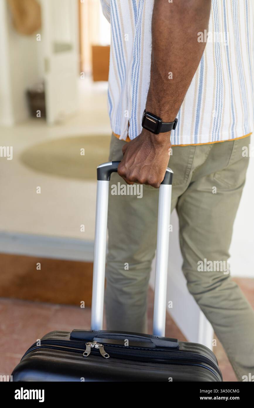 Mann mit Koffer in gemütliches Haus, bereit für einen erholsamen Urlaub Stockfoto