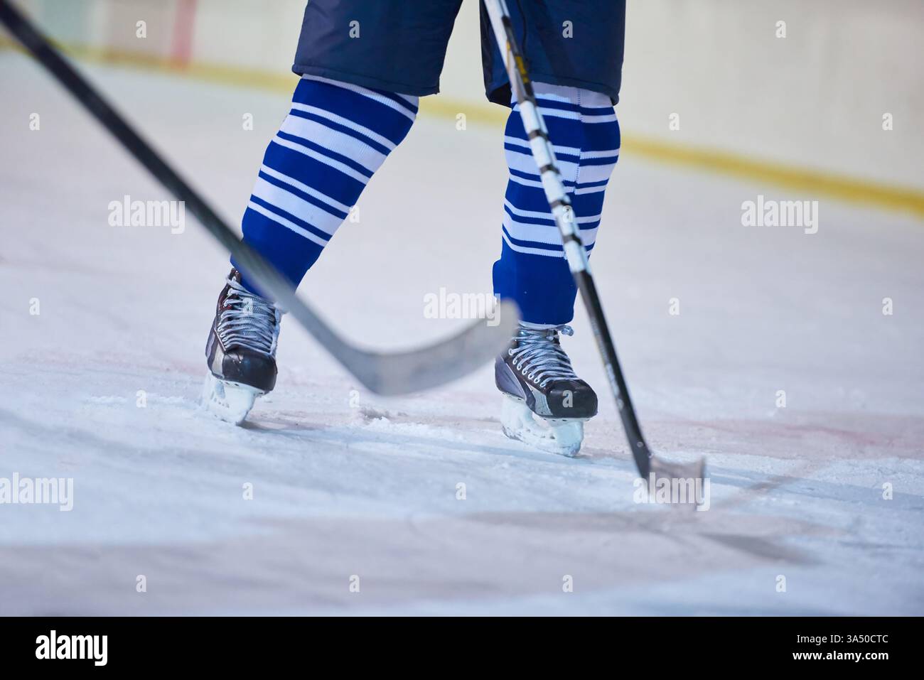 Ein actiongeladenes Eishockeyspiel auf der Eisbahn zeigt Spieler, die um den Puck kämpfen. Mit Helmen vermitteln die Athleten Geschwindigkeit, Geschick und Teamwettbewerb. Ideal für Wintersportkampagnen, Sportmarketing und sportliches Training. Stockfoto