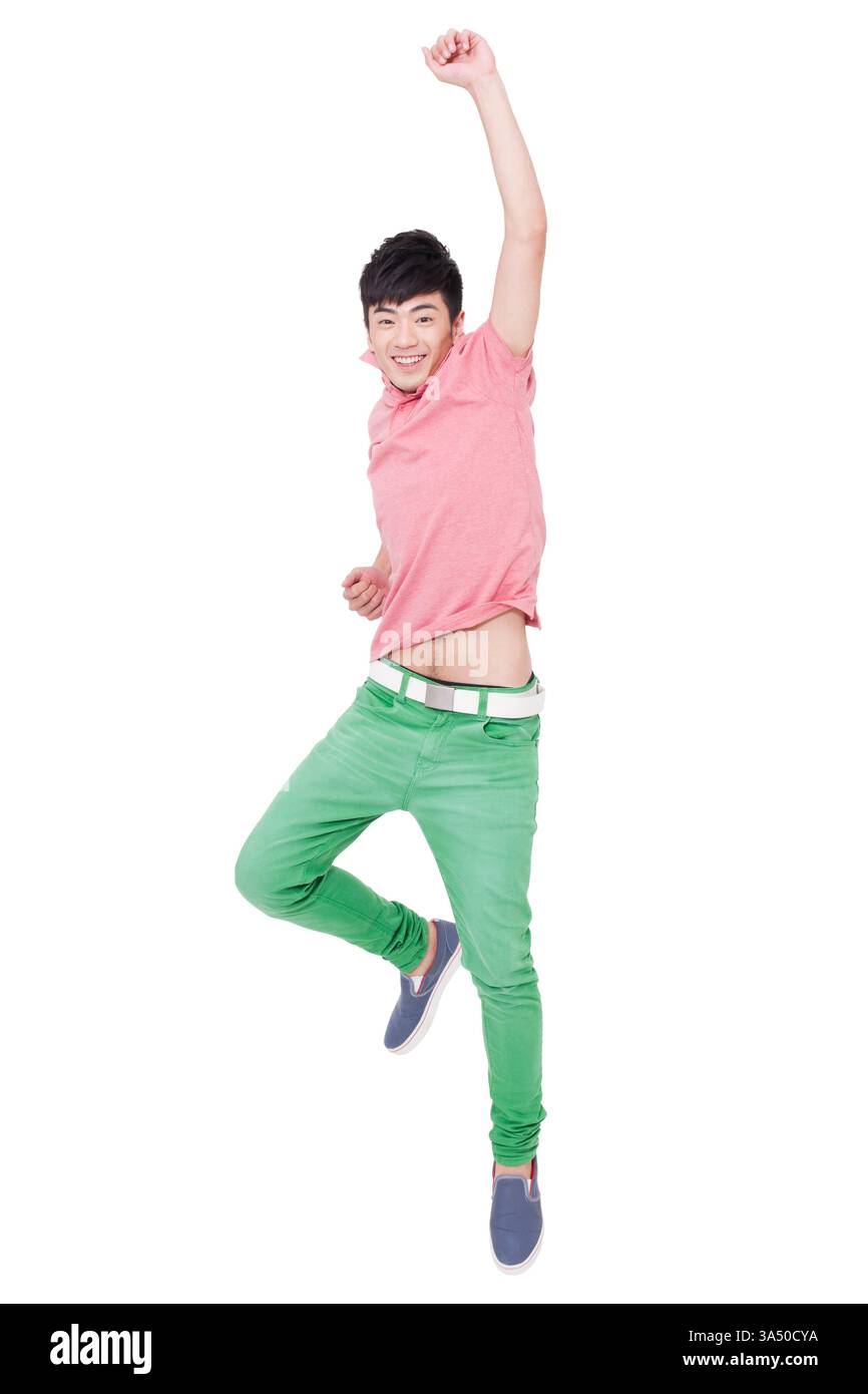 Ein glücklicher junger Chinese springt mit erhobenen Armen mitten in die Luft und drückt Lebensfreude aus. Diese lebendigen Lifestyle-Bilder eignen sich hervorragend für Jugend-, Reise- und Fitness-Branding. Der Kopierbereich und der klare Hintergrund erleichtern das Überlagern von Text für Marketingmaterialien. Stockfoto