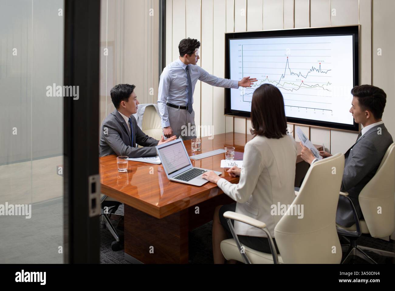Ein chinesischer Geschäftsmann leitet ein Team-Meeting in einem Büro. Er leitet die Diskussion und präsentiert Pläne in einem kollaborativen, professionellen Umfeld. Stockfoto