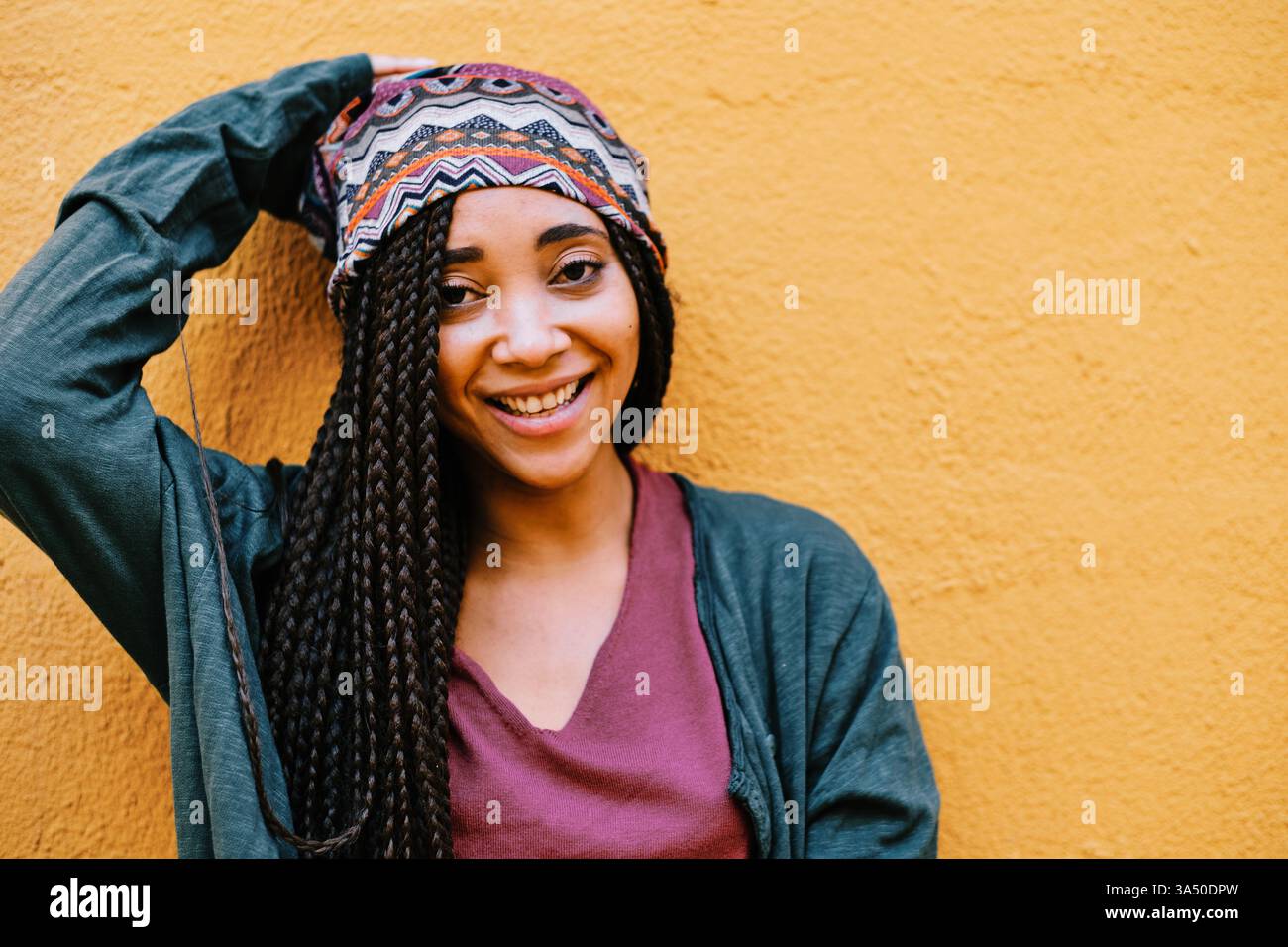 Porträt einer schwarzen Frau mit Zöpfen im Freien. Die natürliche Beleuchtung und das moderne Design betonen Individualität und Schönheit in einem echten Menschenkonzept. Ideal für vielfältige Präsentationen in Mode-, Lifestyle- oder Empowerment-Kampagnen. Stockfoto