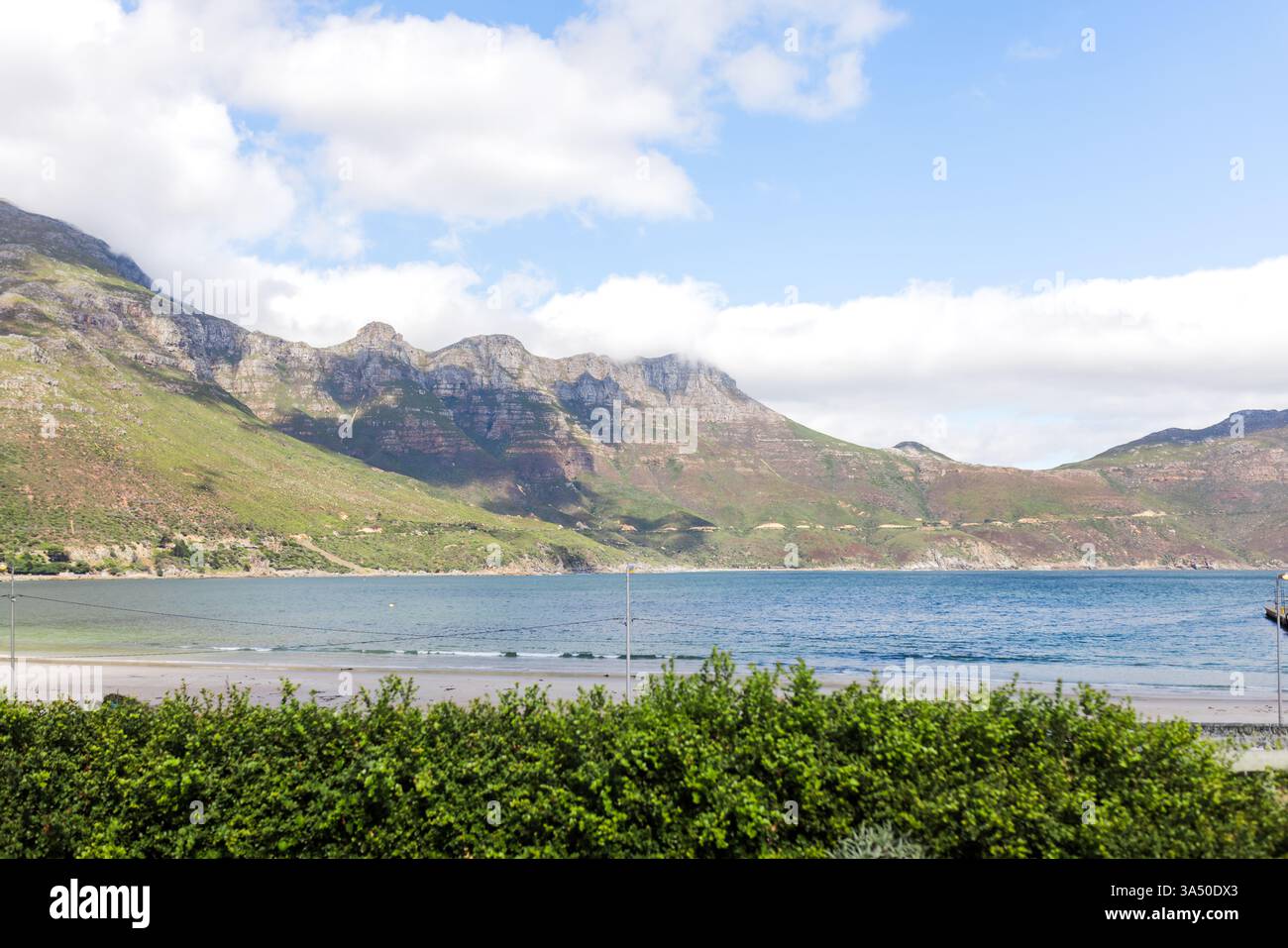 Malerischer Blick auf die Küste mit üppigen Bergen und ruhigem Meer unter blauem Himmel Stockfoto Malerischer Blick auf die Küste mit üppigen Bergen und ruhigem Meer unter blauem Himmel Stockfoto