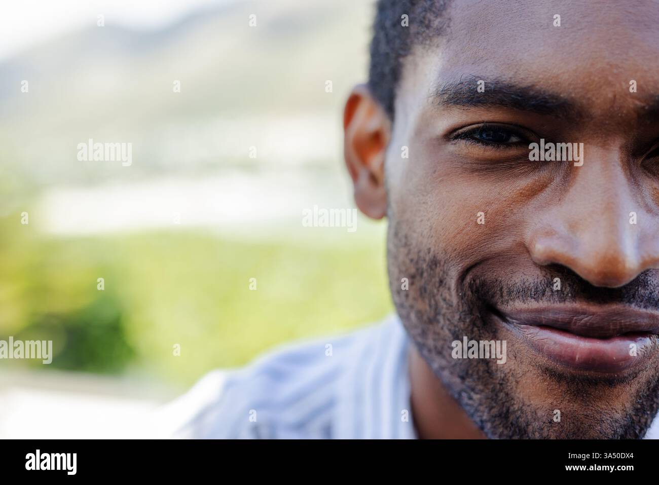 Ein lächelnder afroamerikanischer Mann genießt Outdoor-Urlaub, fühlt sich entspannt und zufrieden Stockfoto