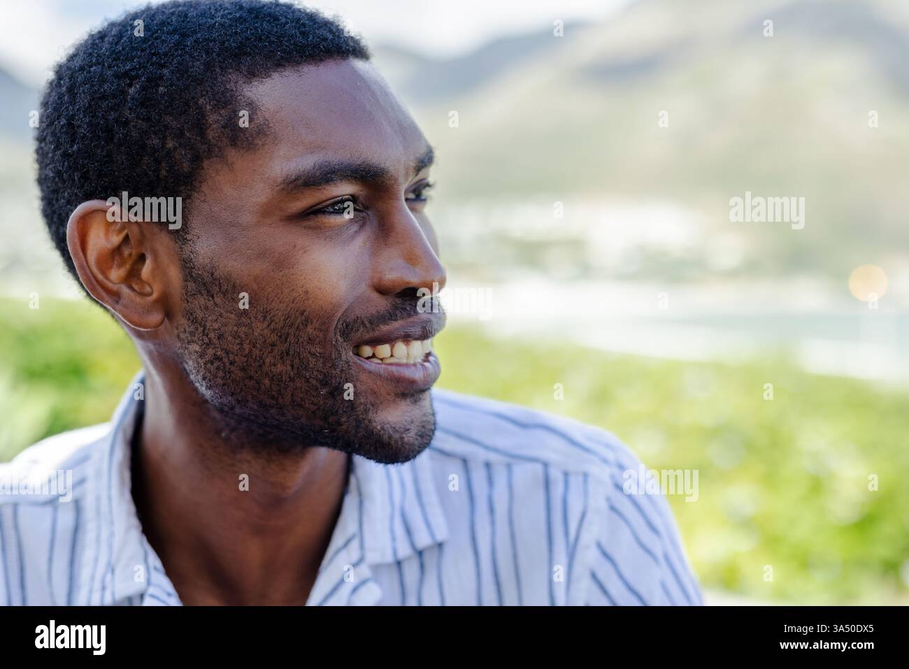 Ein lächelnder afroamerikanischer Mann genießt einen sonnigen Tag im Freien im Urlaub Stockfoto